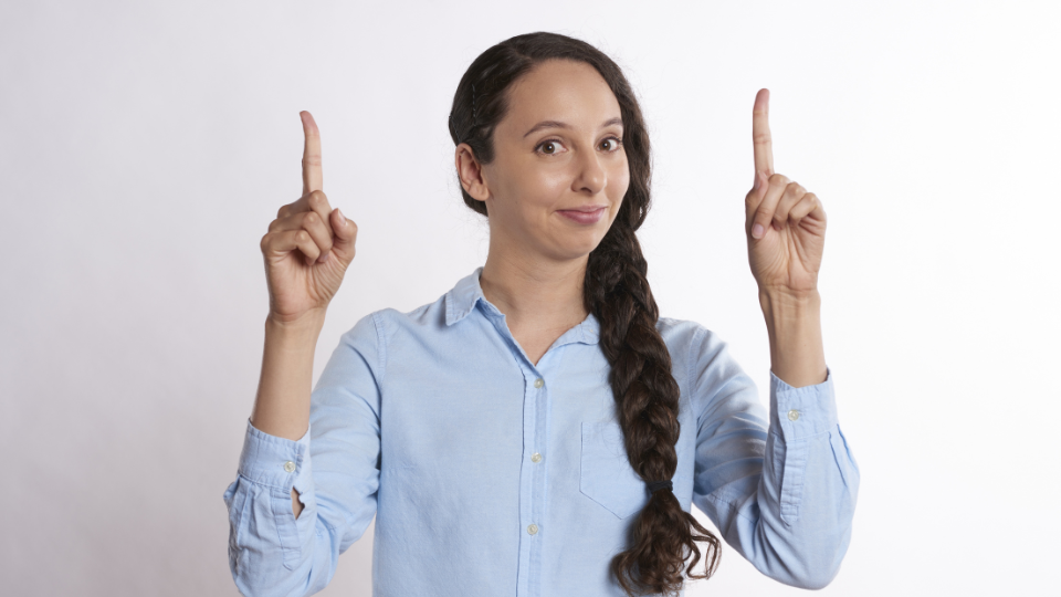 両手の人差し指を立てている女性